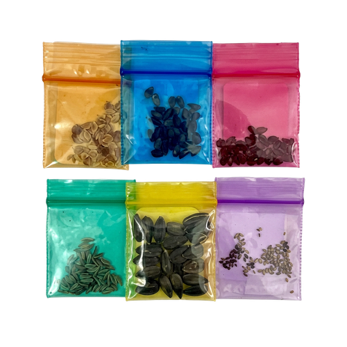 Six small translucent resealable pouches arranged in a 2x3 grid on a white background, each in a different color: amber, blue, pink, teal, yellow, and lavender. The pouches contain small dark seeds or seed-like pieces.