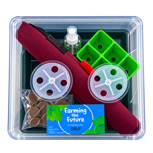 A comprehensive farm tool kit in a clear plastic storage container, featuring a dark green tray with a burgundy rolled fabric cover, a green plastic wheel, two clear plastic spool covers, a small spray bottle, a bag of brown organic material, and a blue 'Farming the Future' card.